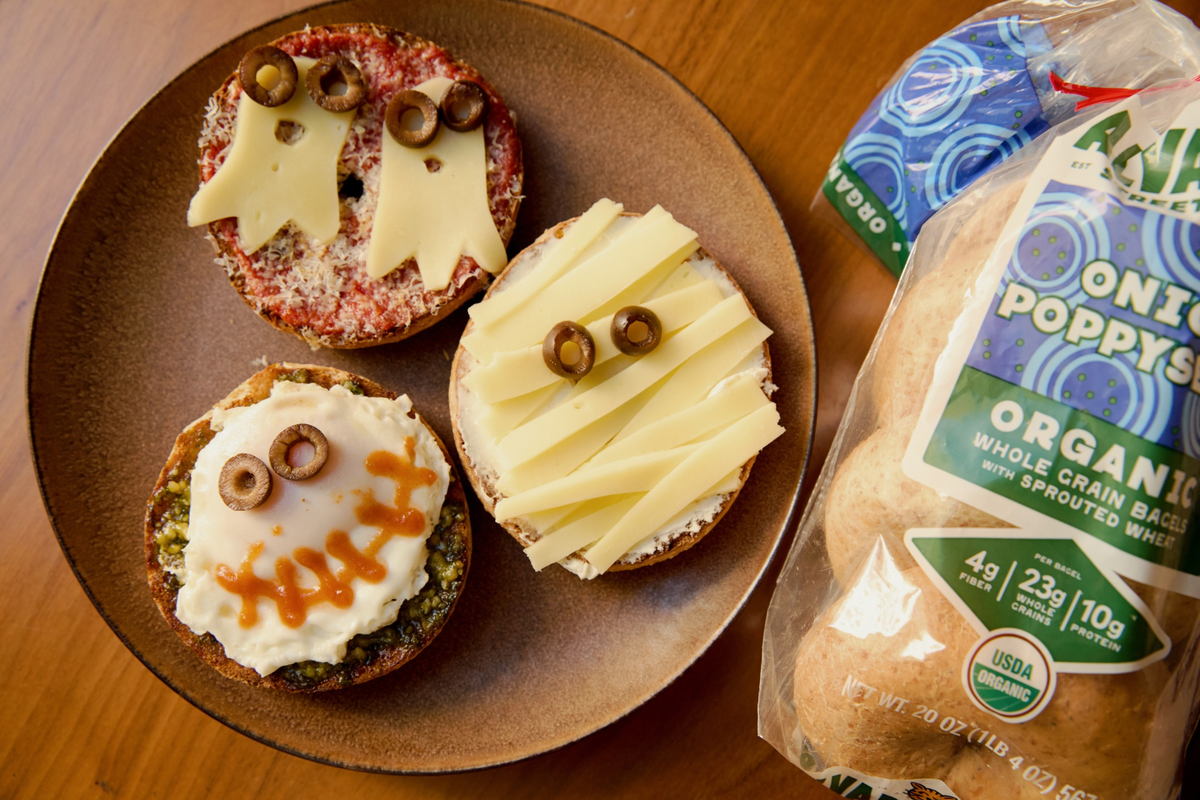 Three bagels on a plate with toppings that look like mummies and ghosts