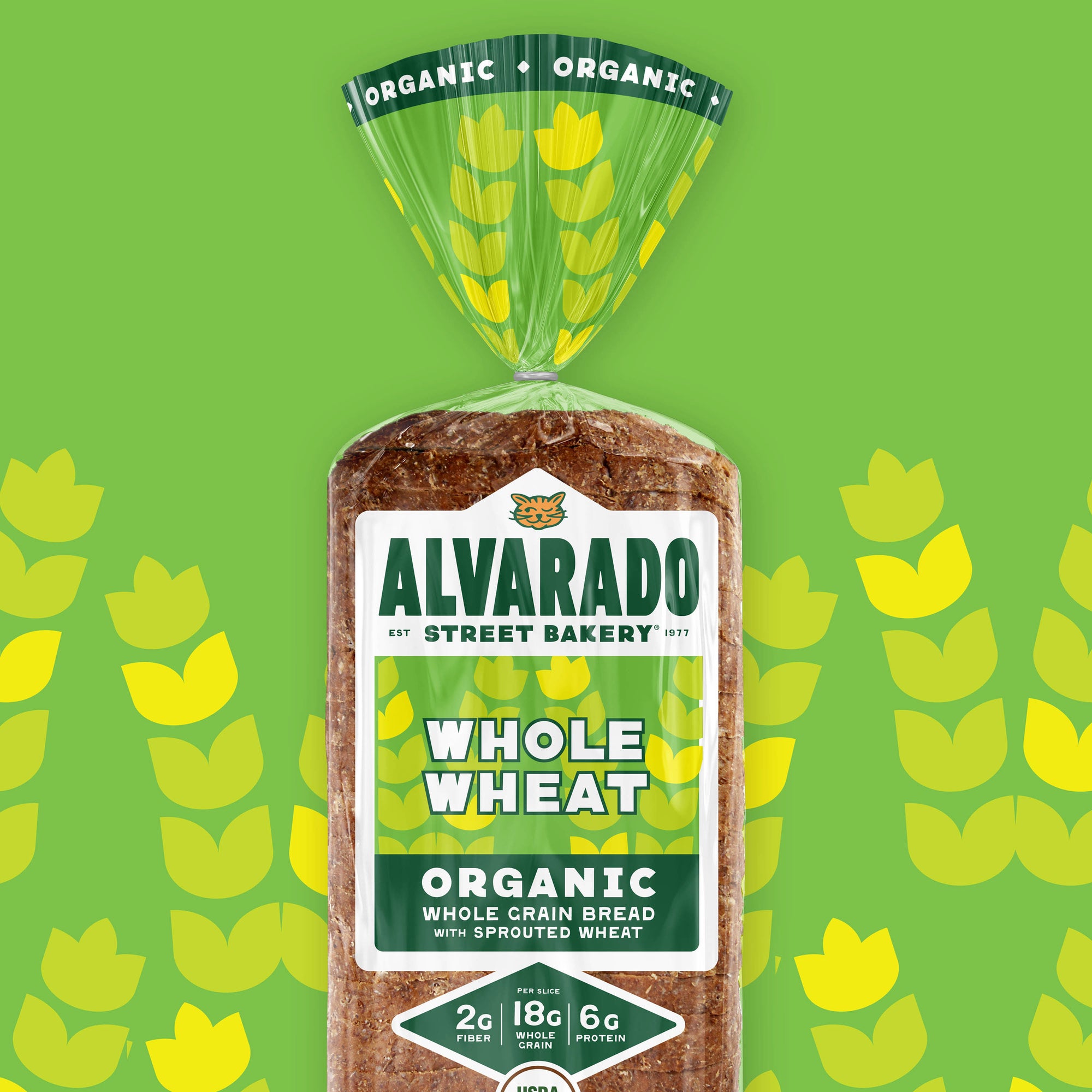 Packaged loaf of Alvarado Street Bakery whole wheat bread on a green background with wheat pattern