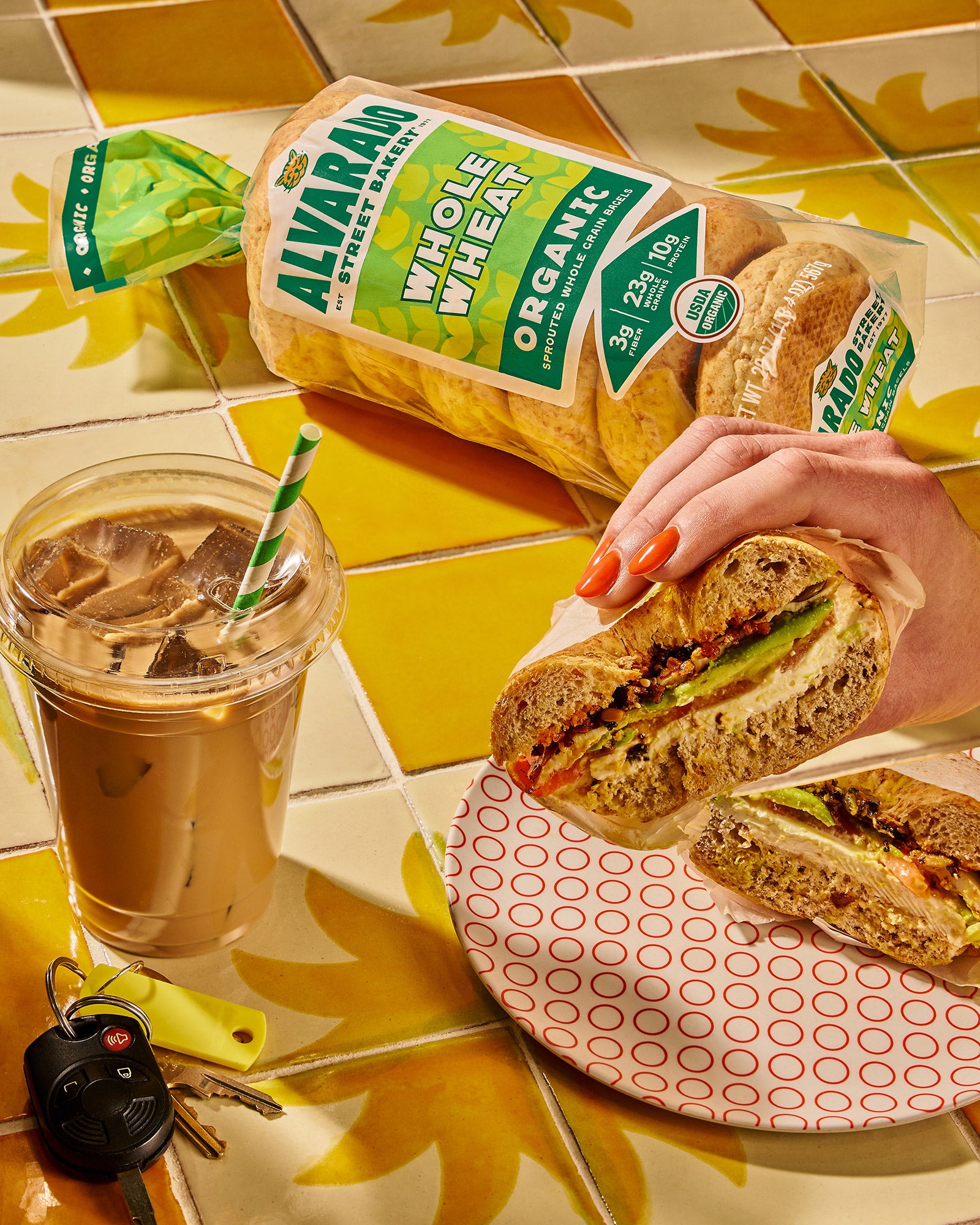 Person holding a sandwich with Alvarado Organic bread on a yellow tile background