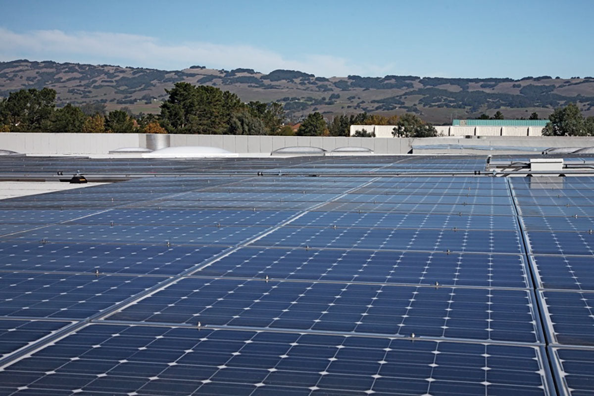 Solar panels on a roof with a clear sky and mountains in the background